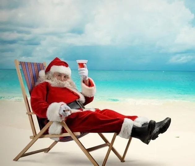 Happy Holidays from 5350 The Pourhouse Santa in a chair drinking a beer on Holmes Beach